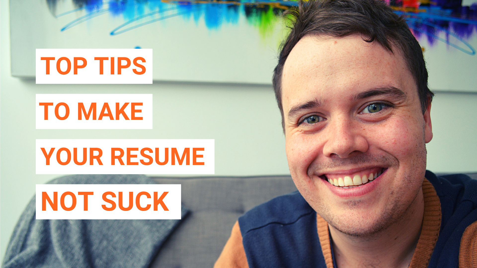 Close-up of a smiling man with large orange text blocks reading 'TOP TIPS', 'TO MAKE', 'YOUR RESUME', 'NOT SUCK' laid over a light background.